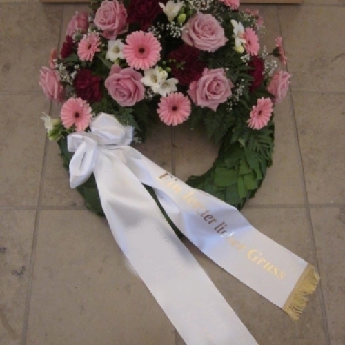 Begravelseskrans med rosa blomster og hvidt bånd