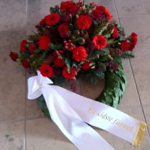 Begravelseskrans med gule roser og blomster med hvidt bånd