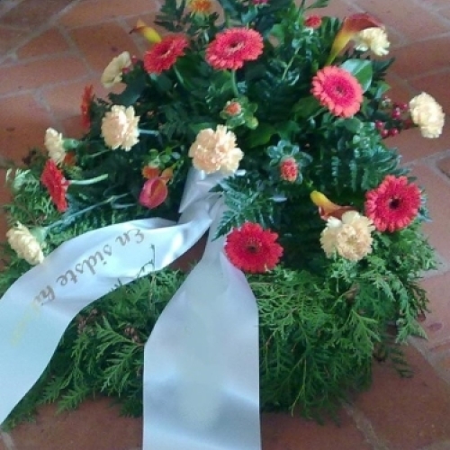 Begravelseskrans med røde og gule blomster med bånd