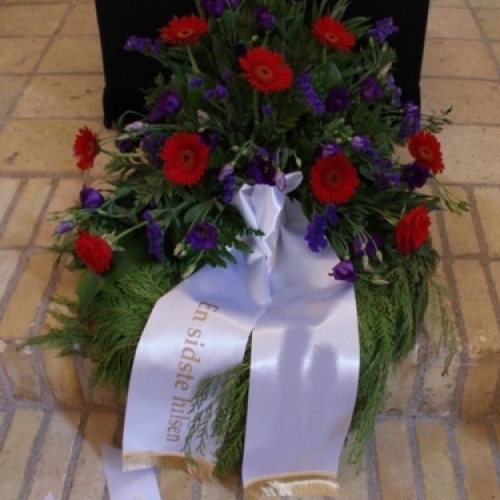 Begravelseskrans med hvide blomster og grønt med bånd