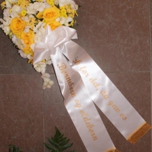 Begravelseskrans med gule roser, hvide blomster og hvidt bånd