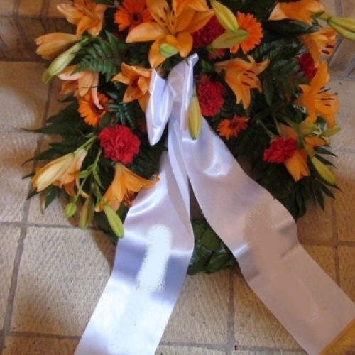 Begravelseskrans med hvide roser og lilla blomster med hvidt bånd