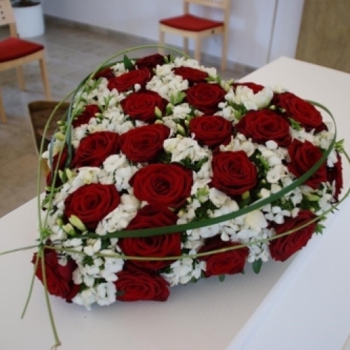 Kistepynt med gule og hvide blomster arrangeret på kiste i kirkerum