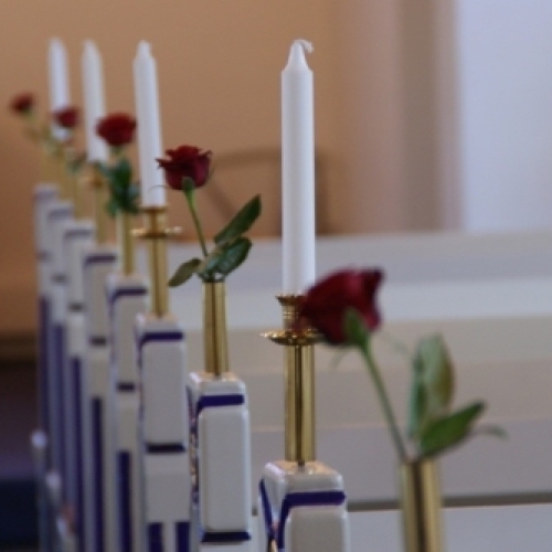 Kirkepynt med hvide lys og røde roser langs kirkebænkene