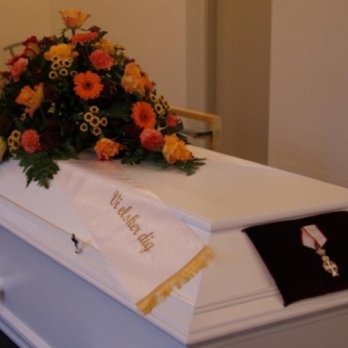 Hjerteformet kistepynt med røde roser og hvide blomster