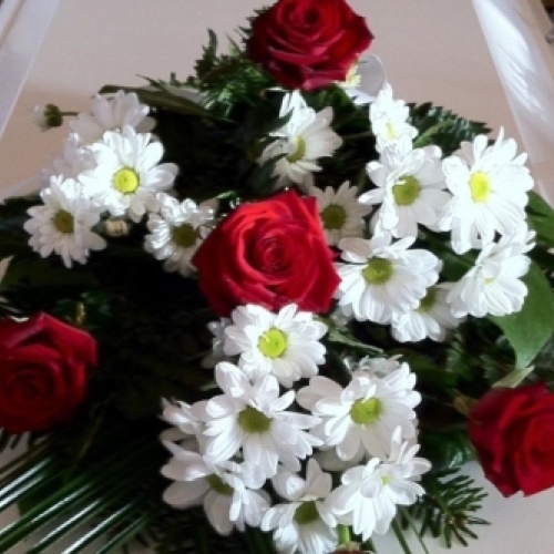 Kistedekoration med gule roser arrangeret på kiste