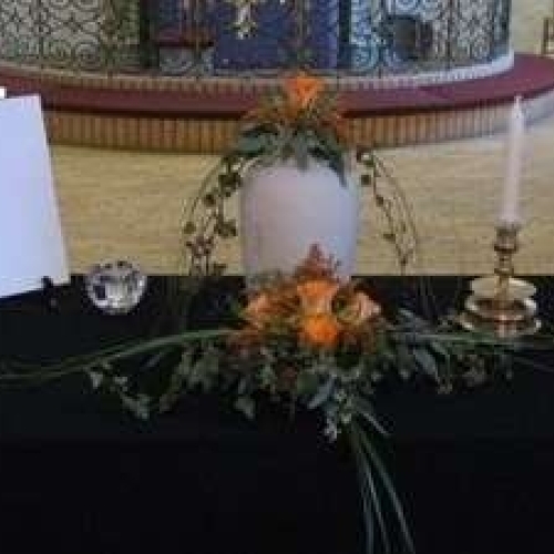 Urnedekoration i kirke med blomster og lys